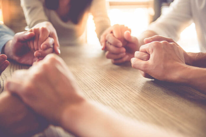 Cropped,Image,Of,Beautiful,Business,Team,Holding,Hands,And,Praying