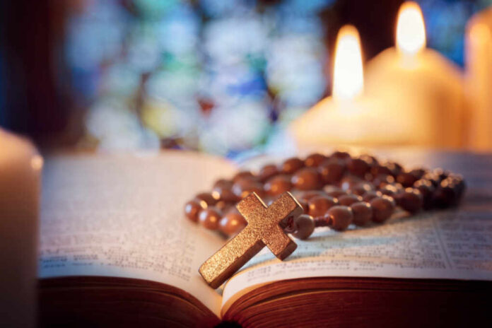 Rosary,Beads,And,Crucifix,Cross,On,Holy,Bible,With,Candles