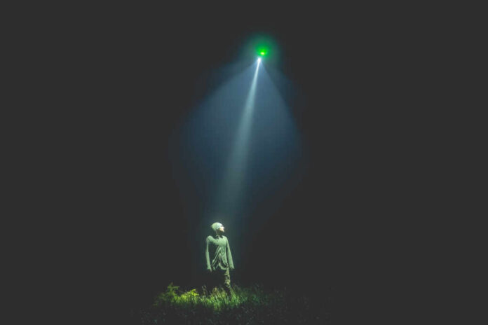 The,Ufo,Shines,On,A,Man,Standing,On,The,Grass.