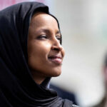 Woman wearing a black hijab looking thoughtfully into the distance