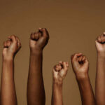Free Speech Clash: UF Faces Legal Challenge A group of diverse hands with raised fists against a brown background
