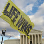 A large yellow flag with the text LIFE WINS waving in front of the Supreme Court building