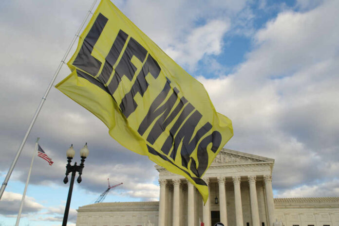 A large yellow flag with the text LIFE WINS waving in front of the Supreme Court building