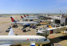 View of multiple Delta Airlines planes parked at an airport terminal with ground crew and vehicles
