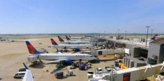 View of multiple Delta Airlines planes parked at an airport terminal with ground crew and vehicles