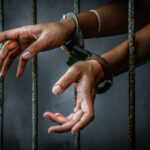Caught on Camera: Brutality Shatters Family Outing Hands in handcuffs reaching through prison bars