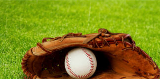 A baseball glove with a baseball resting inside, set on green grass