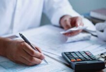 ALARMING Trends: UK Families Face Dire Choices A person writing on financial documents with a calculator nearby