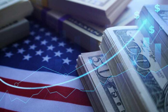 shutterstock_2070666464.jpg Stacks of US dollar bills on an American flag with financial graphs overlay