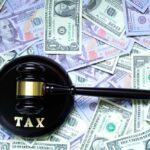 Billion-Dollar Loss: California’s Tax Tragedy A gavel with the word 'TAX' on it placed on a background of US dollar bills