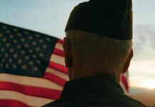 Historic Honor: WWII Vet Named Fan of the Year A veteran in uniform standing in front of an American flag during sunset