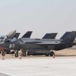 F-35 military jets parked on an airfield with crew members nearby