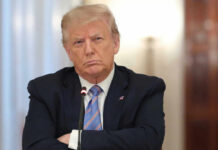 A serious-looking man in a suit with arms crossed during a meeting