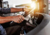Close-up of a truck driver's hands on the steering wheel inside a vehicle
