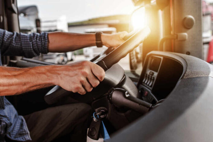 shutterstock_1040943541.jpg Close-up of a truck driver's hands on the steering wheel inside a vehicle