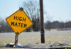 A high water warning sign near a flooded area