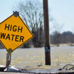 A high water warning sign near a flooded area