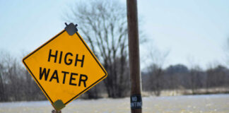A high water warning sign near a flooded area