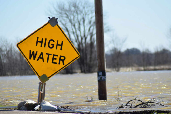A high water warning sign near a flooded area