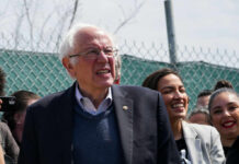 MASSIVE Union Rally Shakes NYC A group of people at an outdoor political rally, with a smiling man speaking and a woman laughing in the foreground