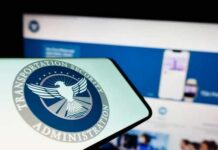 Close-up of a mobile device displaying the TSA logo with a blurred background of a website