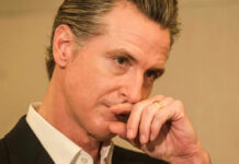 Close-up of a man in a suit with a thoughtful expression, hand on chin