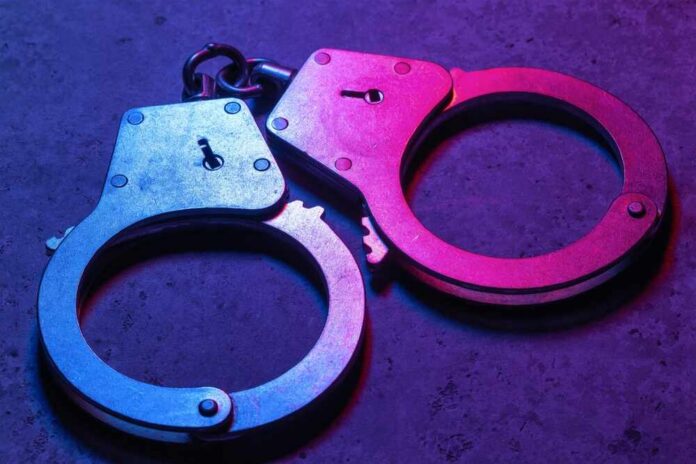 shutterstock_2415931399.jpg Close-up of metallic handcuffs illuminated with neon lights