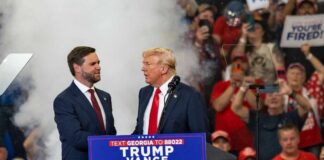 Donald Trump speaking at a political rally with supporters in the background
