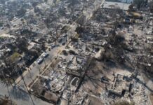 Aerial view of a neighborhood devastated by wildfire, showing burned structures and debris