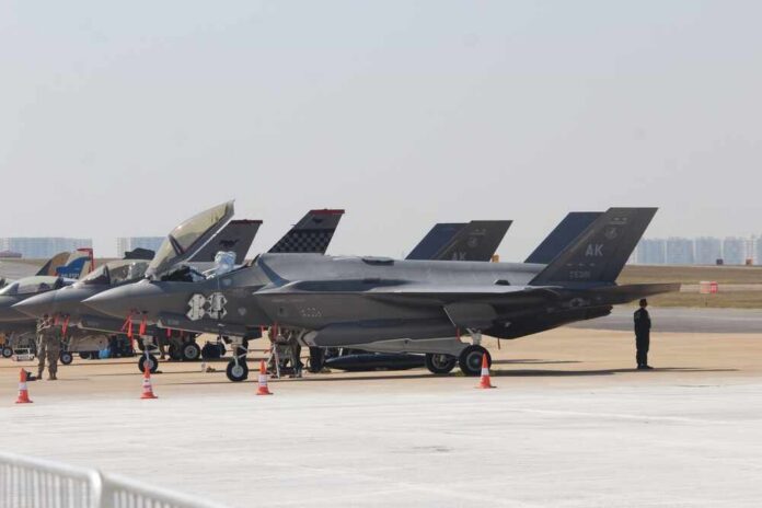 F-35 military jets parked on an airfield with crew members nearby