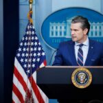 A government official speaking at a podium in front of the White House seal and American flag