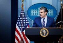 A government official speaking at a podium in front of the White House seal and American flag