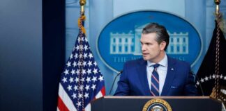 A government official speaking at a podium in front of the White House seal and American flag