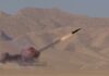 A missile launching into the sky with smoke and flames in a desert setting