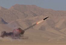 A missile launching into the sky with smoke and flames in a desert setting