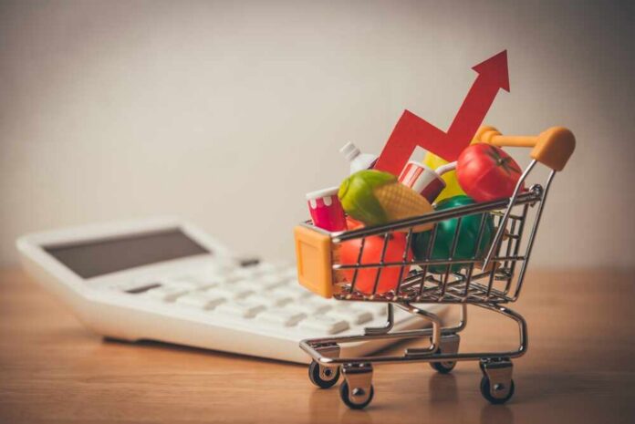A shopping cart filled with colorful grocery items next to a calculator and an upward trend arrow