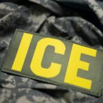 Close-up of a military patch with the letters ICE on a camouflage background
