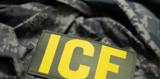 Close-up of a military patch with the letters ICE on a camouflage background