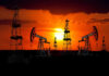 Silhouetted oil rigs against a vibrant sunset