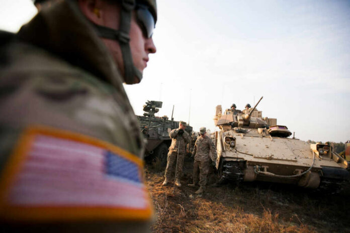 Soldiers in military gear coordinating near armored vehicles during training