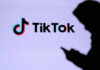 Silhouette of a person using a mobile device in front of the TikTok logo