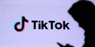 Silhouette of a person using a mobile device in front of the TikTok logo