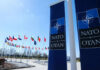 NATO flags displayed in front of the NATO headquarters under a clear blue sky
