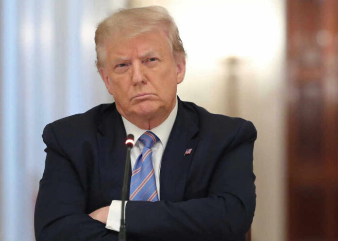 A serious-looking man in a suit with arms crossed during a meeting