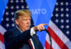 A man delivering a speech with American flags in the background