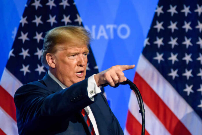 A man delivering a speech with American flags in the background