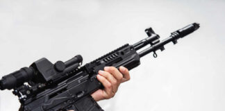Person holding an AK-47 rifle with a scope