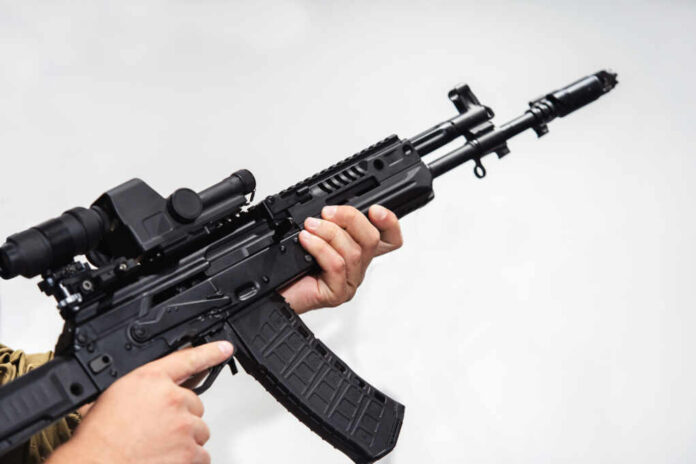 shutterstock_1949380522.jpg Person holding an AK-47 rifle with a scope
