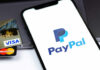 Close-up of a smartphone displaying the PayPal logo next to credit cards