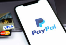 Close-up of a smartphone displaying the PayPal logo next to credit cards